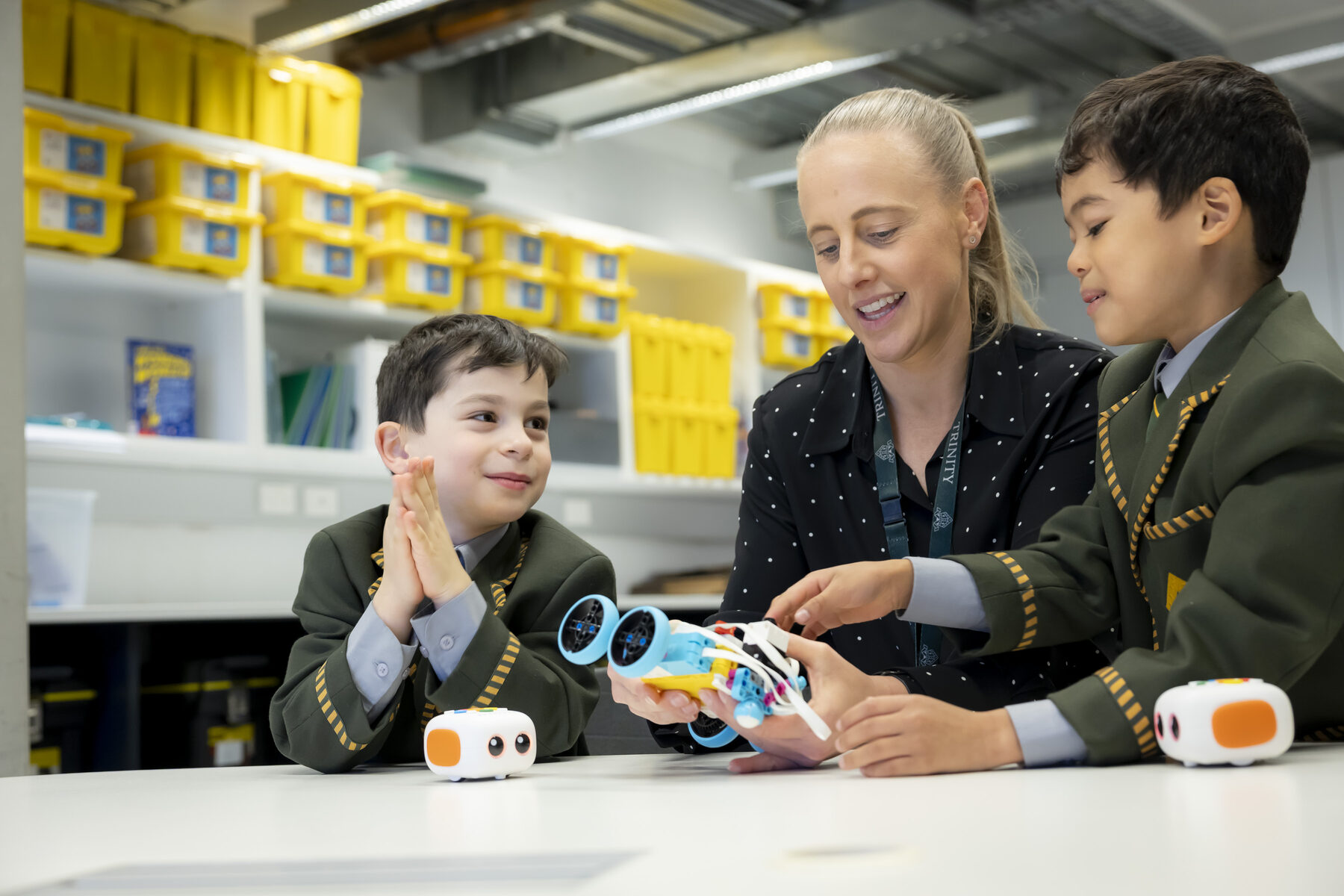 A teacher guiding two Prep boys through a hands-on STEM robotics activity