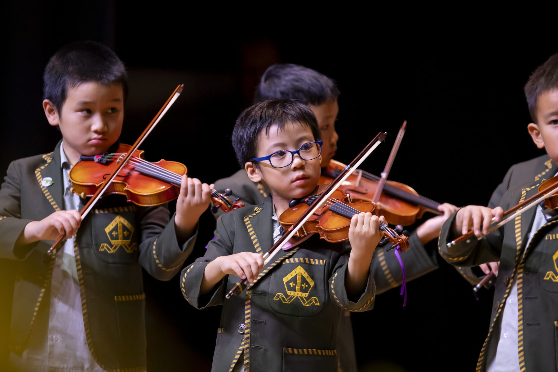 Young Trinity Prep boys playing violin together on stage as part of the specialist Music program